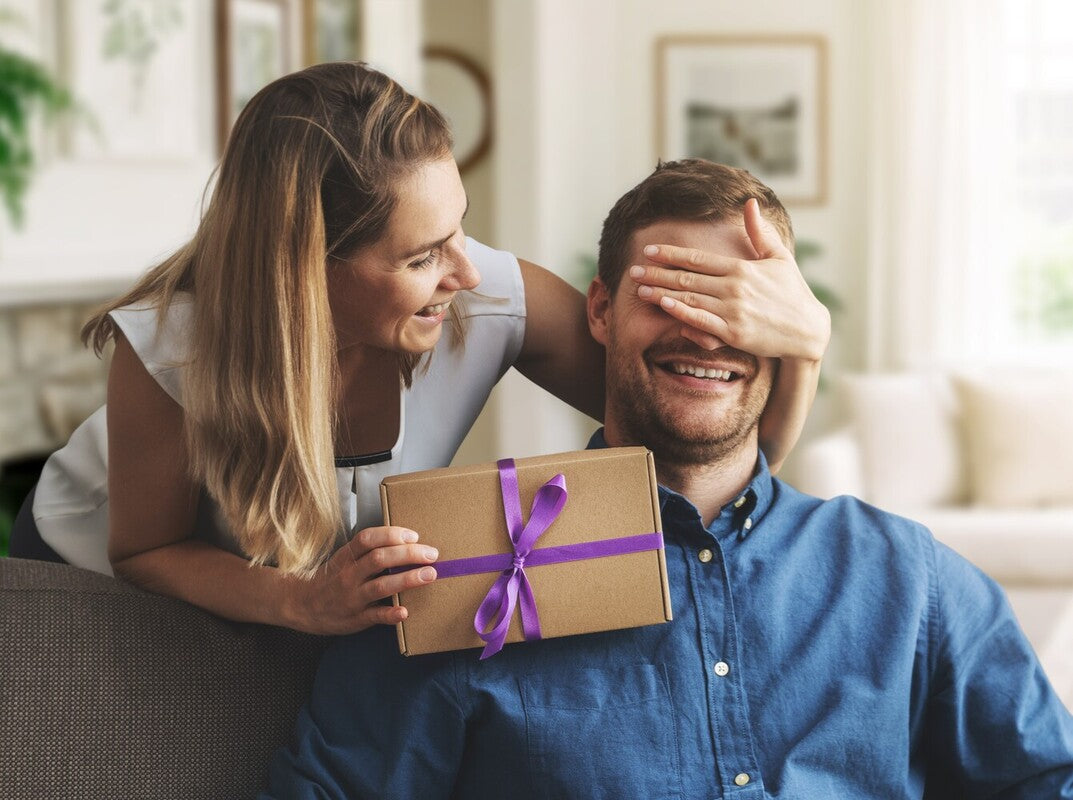 woman excitedly giving the best gift for a husband to her spouse