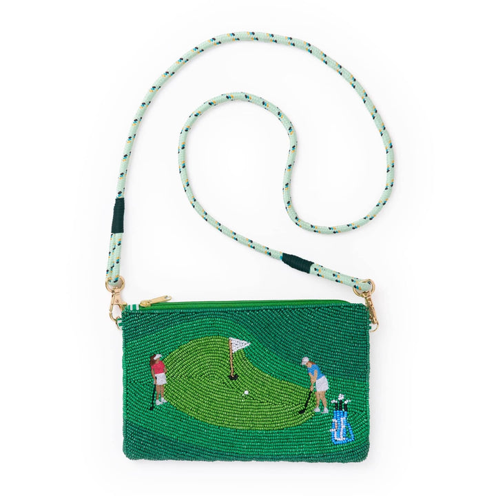 A green beaded clutch bag featuring an embroidered golf course scene with players and a hole flag. The bag has a light green and white patterned woven shoulder strap with gold-tone hardware.
