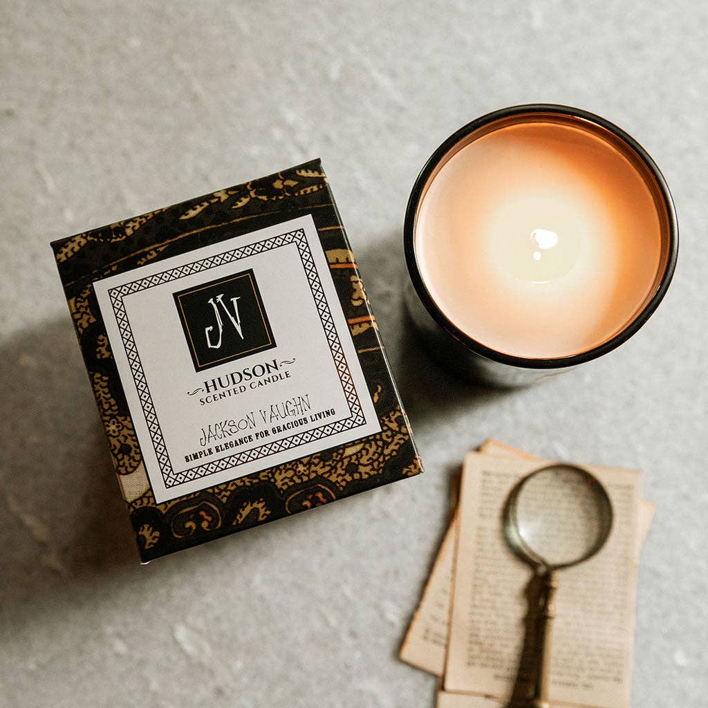 Hudson scented candle with packaging and vintage items on a textured surface