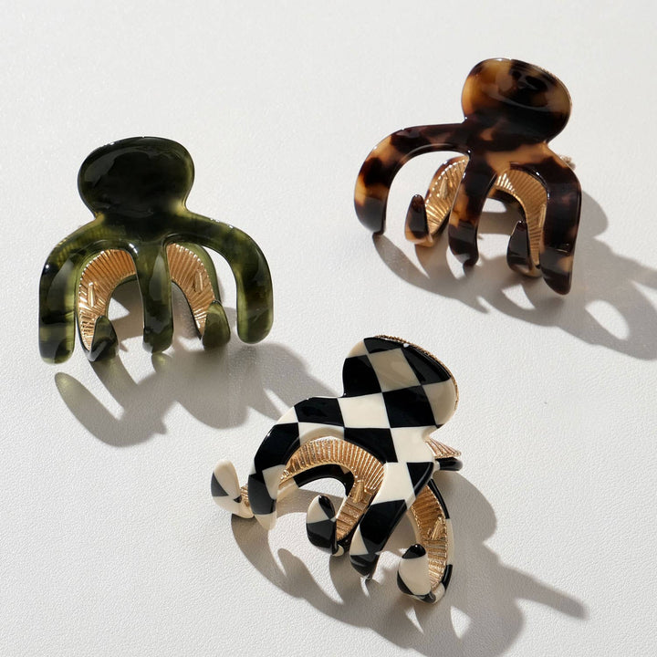Three tortoiseshell and checkered patterned hair clips on a white background