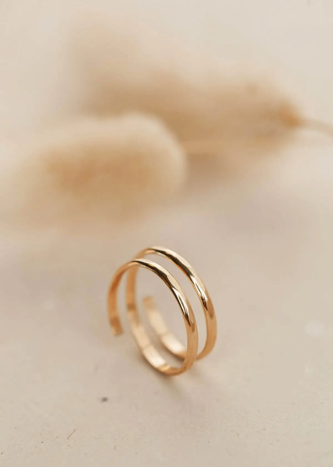Gold hammered wrap ring on a beige background