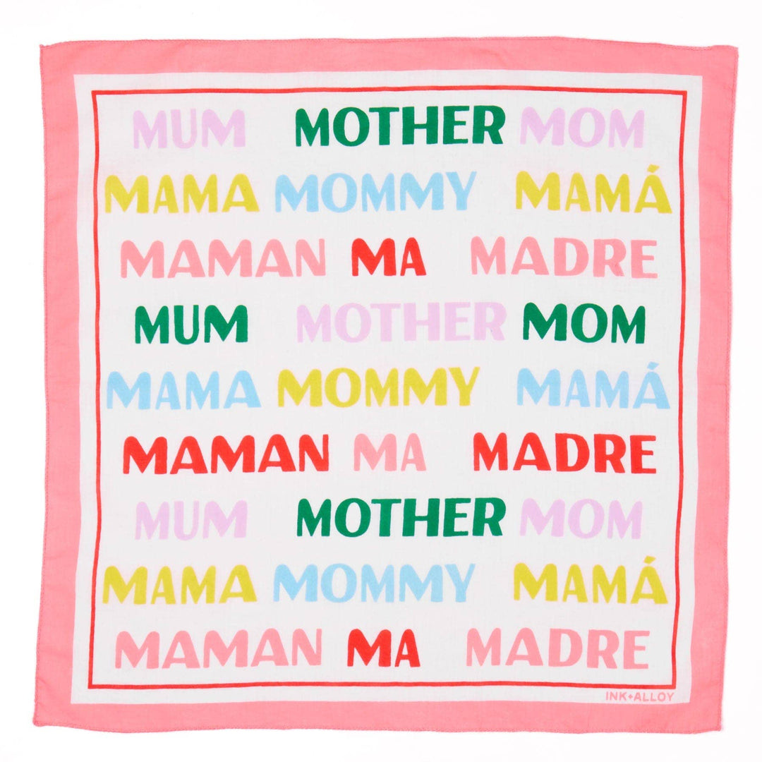 Multicolored text scarf with 'MUM', 'MOTHER', 'MOM', 'MAMA', 'Mommy', 'MAMá', 'MADRE' printed on a white background.