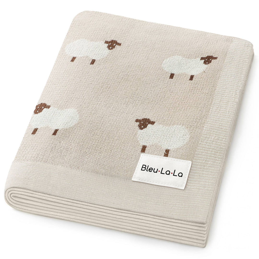 Folded beige blanket with sheep pattern and Bleu-La-La label on a white background