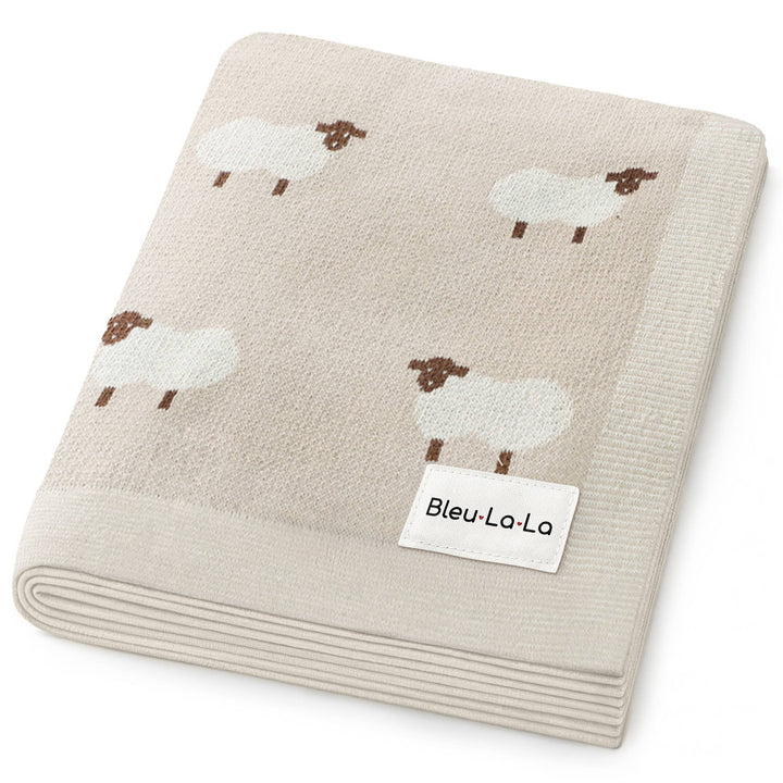 Folded beige blanket with sheep pattern and Bleu-La-La label on a white background