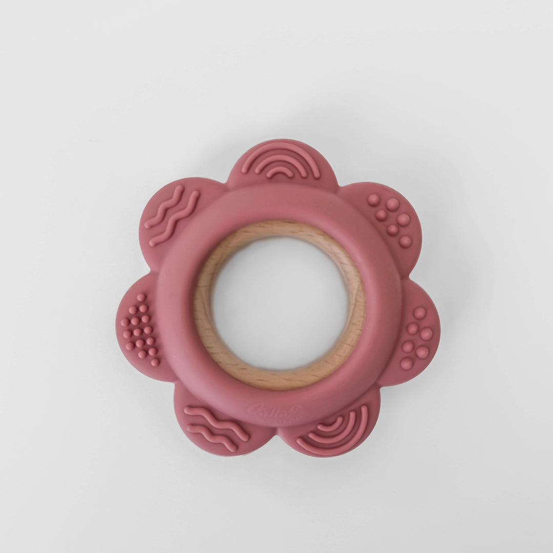 Pink flower-shaped teething ring on a white background