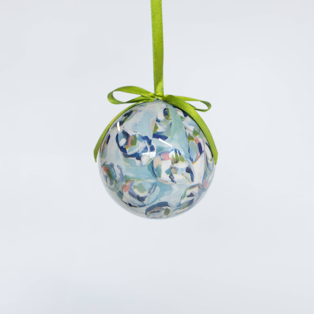 Decorative ball ornament with floral pattern and green ribbon on a light gray background