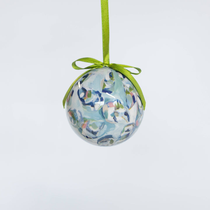Decorative ball ornament with floral pattern and green ribbon on a light gray background