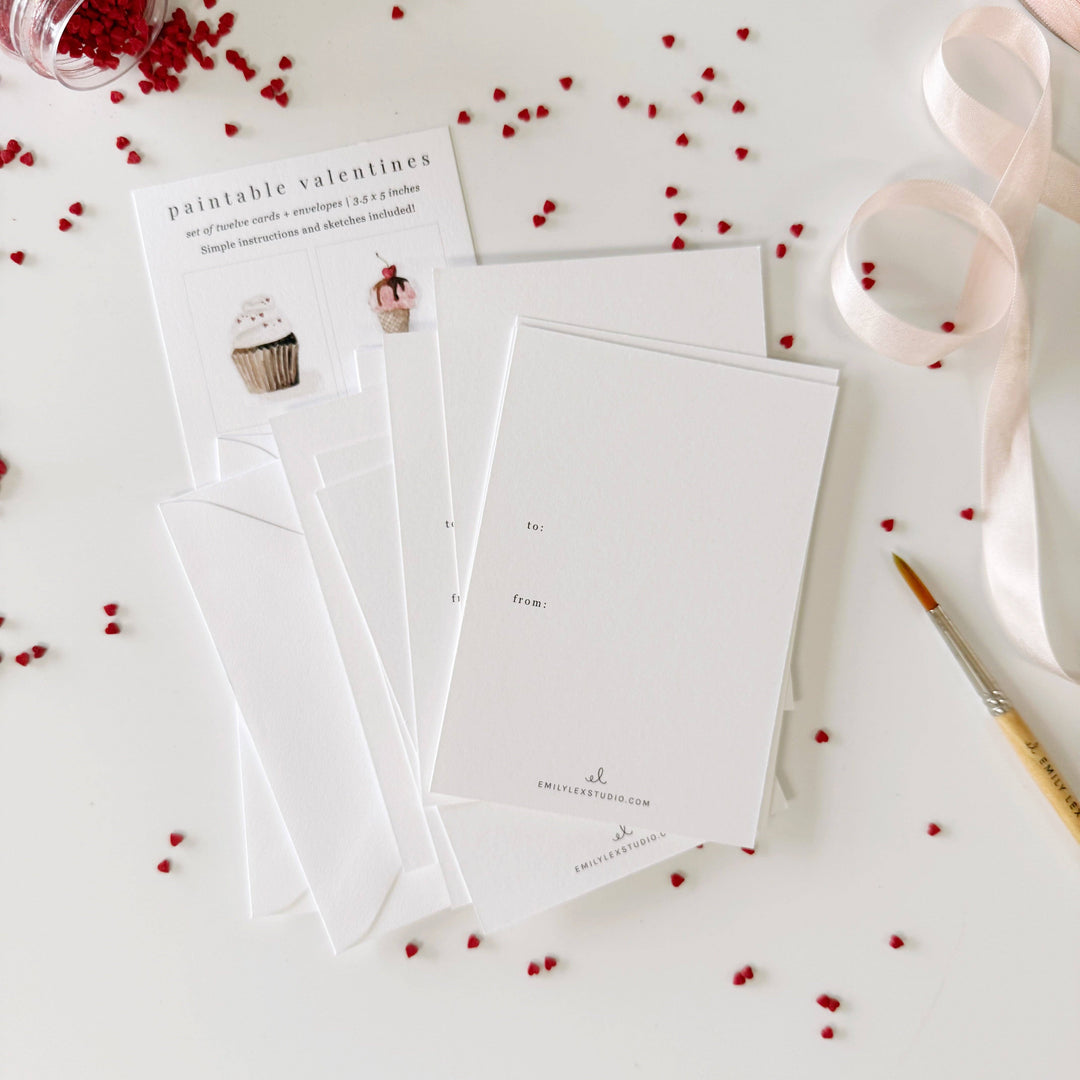 Set of white cards with red heart decorations on a light surface