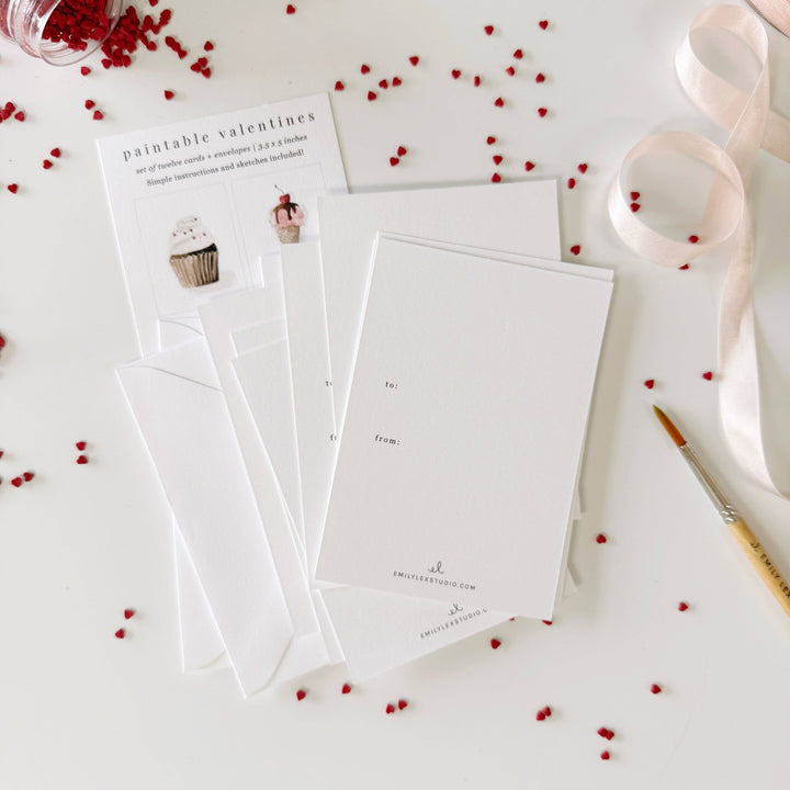 Set of white cards with red heart decorations on a light surface