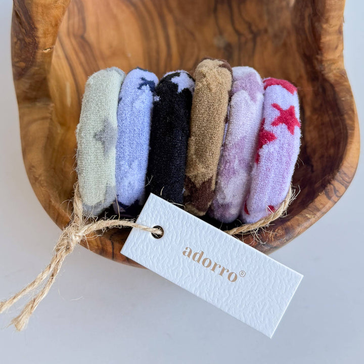 Set of colorful hair ties in a wooden bowl with an 'adorro' tag.
