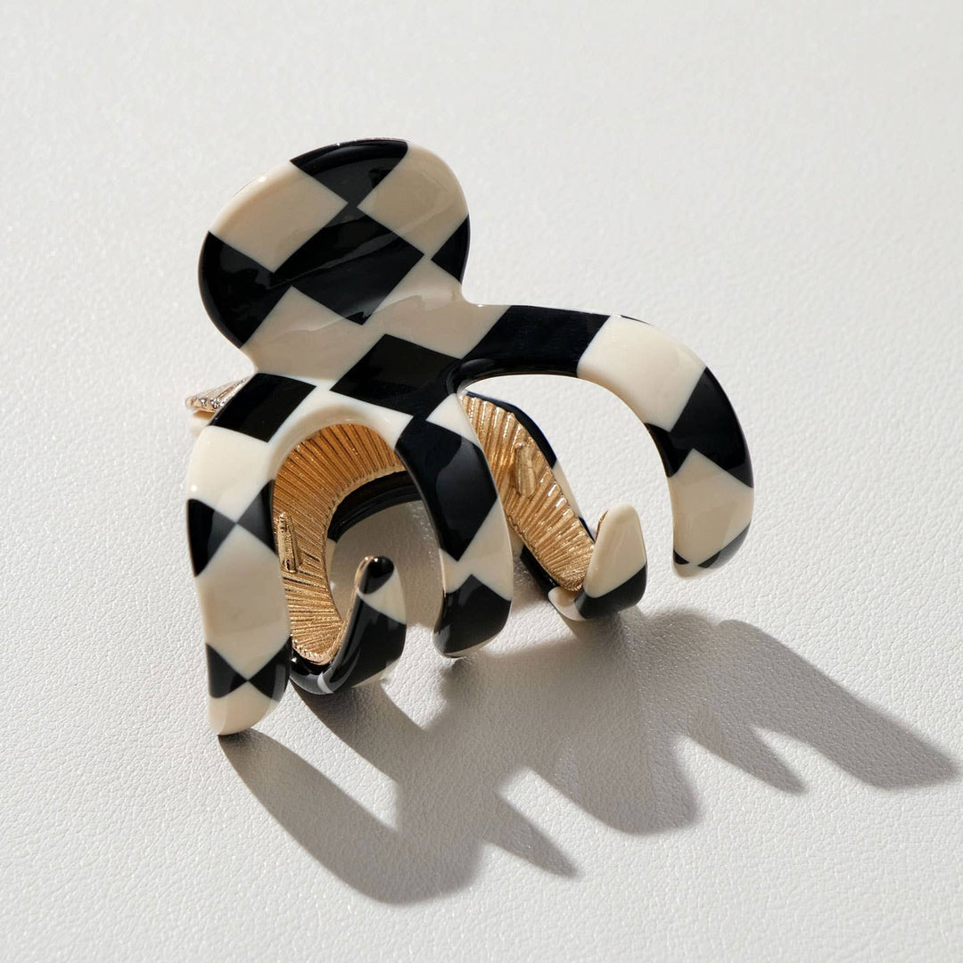 Black and white checkered hair clip with gold accents on a light gray background