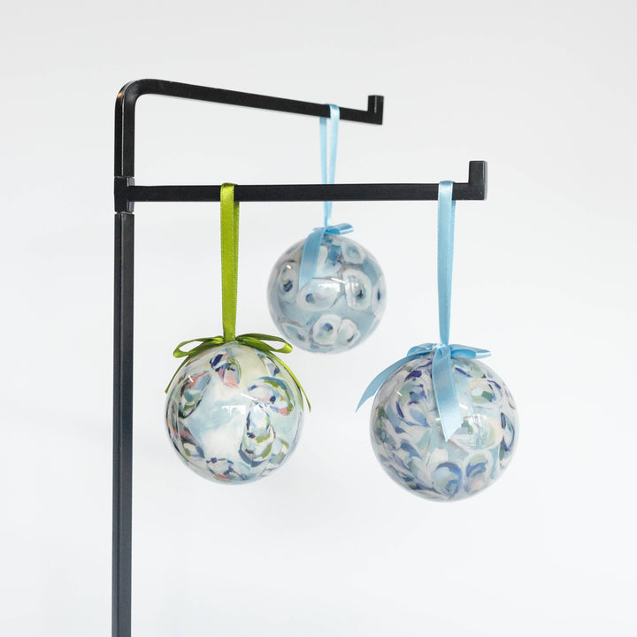 Decorative glass balls with floral patterns hanging on a stand against a white background