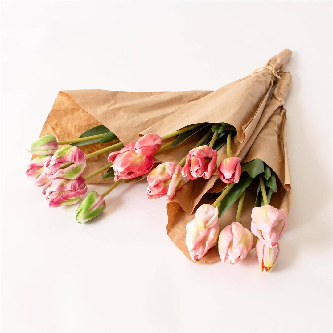 Bouquet of pink tulips wrapped in brown paper on a white background