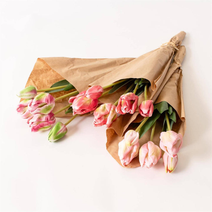 Bouquet of pink tulips wrapped in brown paper on a white background