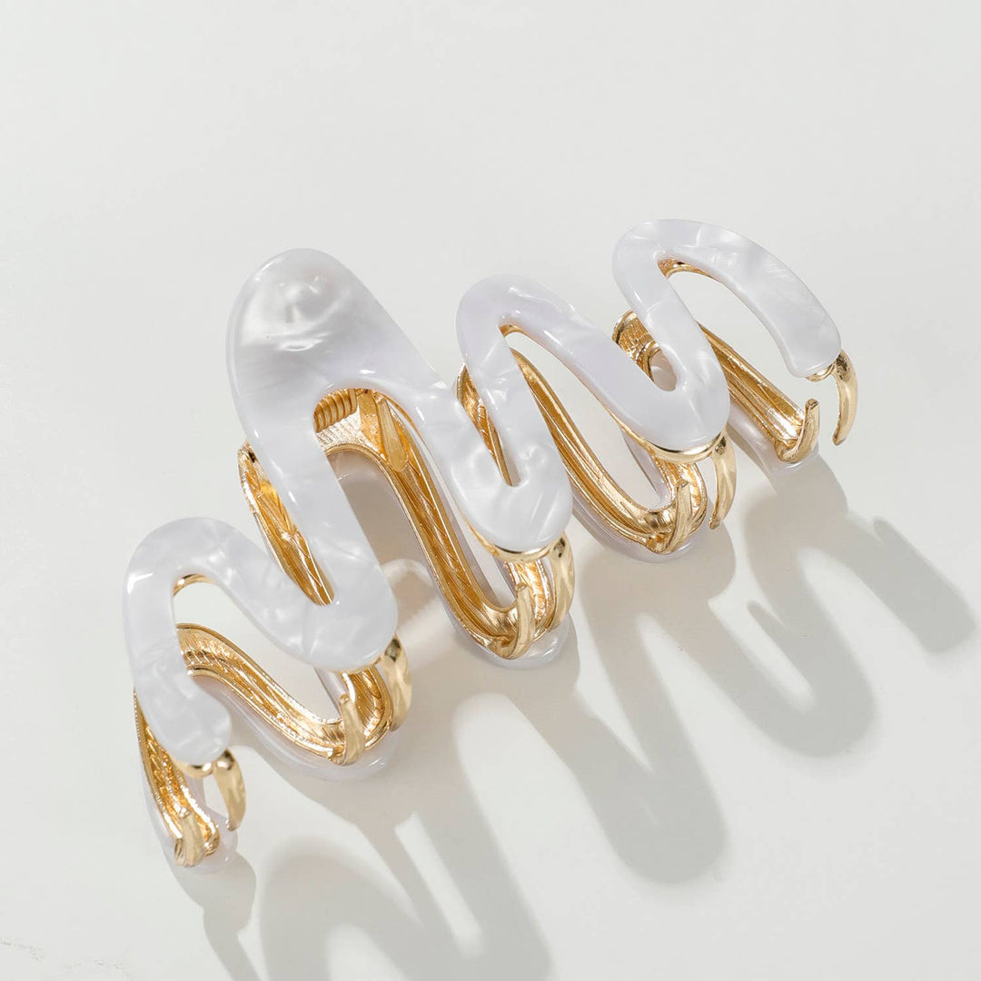 White claw hair clip with gold accents on a light gray background