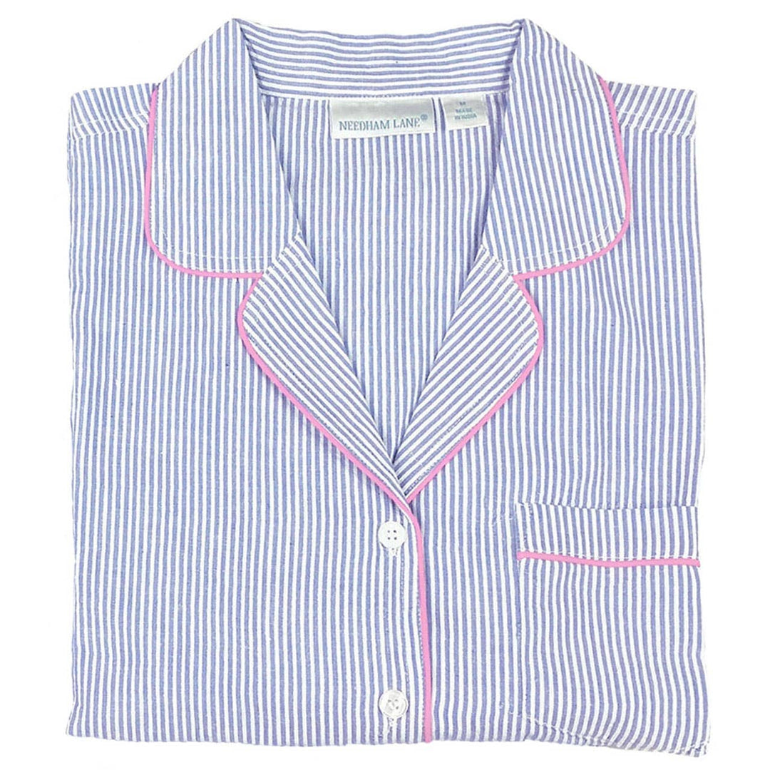 Folded blue and white striped shirt with pink piping on a white background
