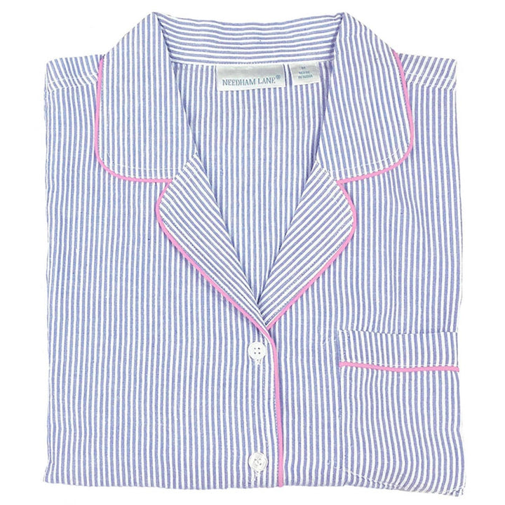 Folded blue and white striped shirt with pink piping on a white background