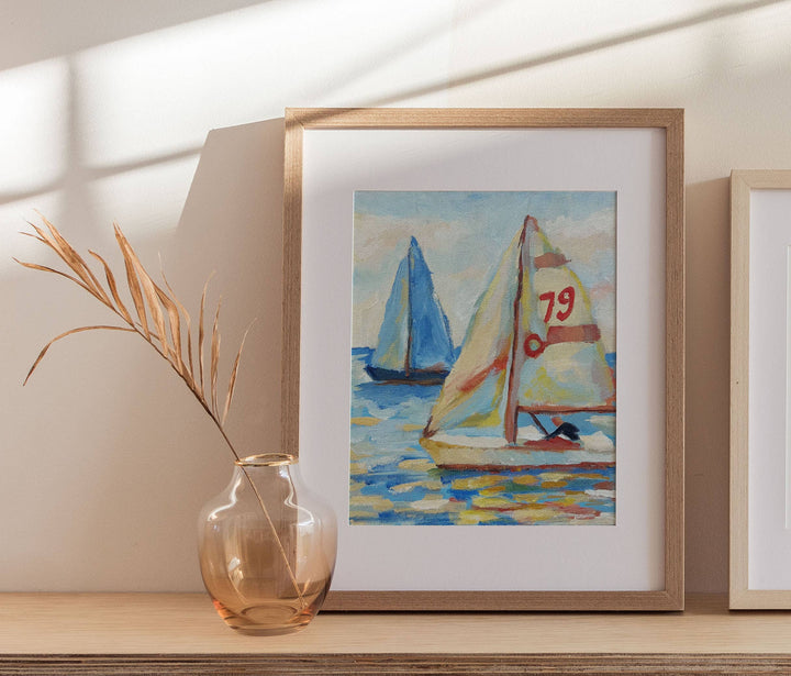 Framed painting of sailboats on a shelf with a vase and plant