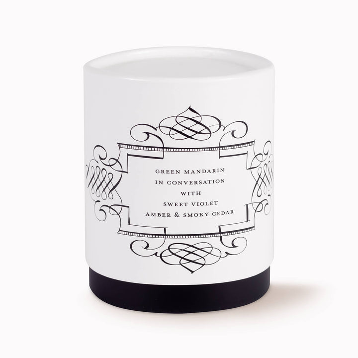White candle with black decorative label on a white background