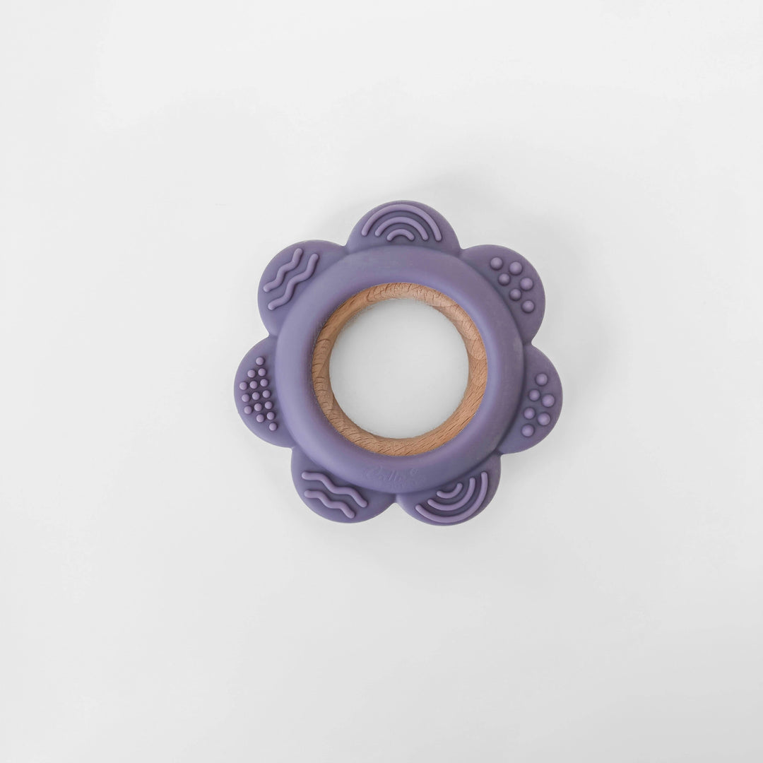 Purple teething ring with wooden center on a white background