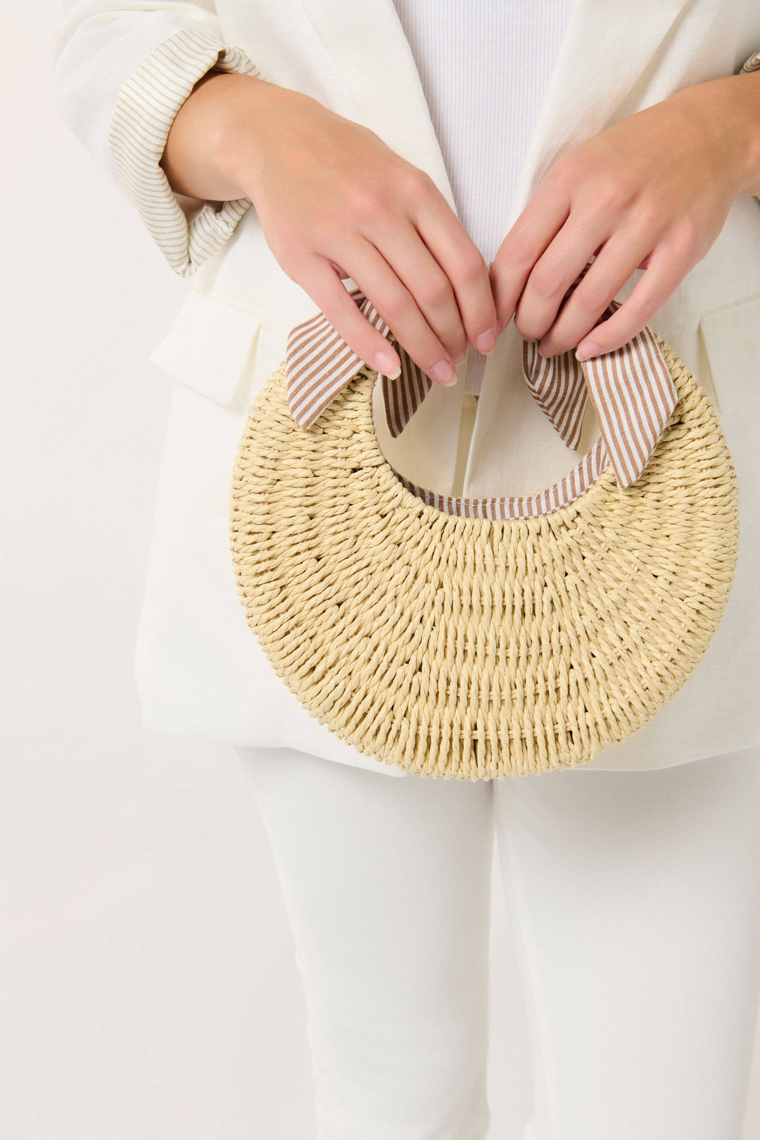 Woven handbag held by a person against a white background