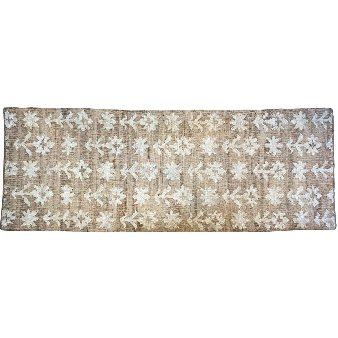 Woven jute rug with floral pattern on a white background