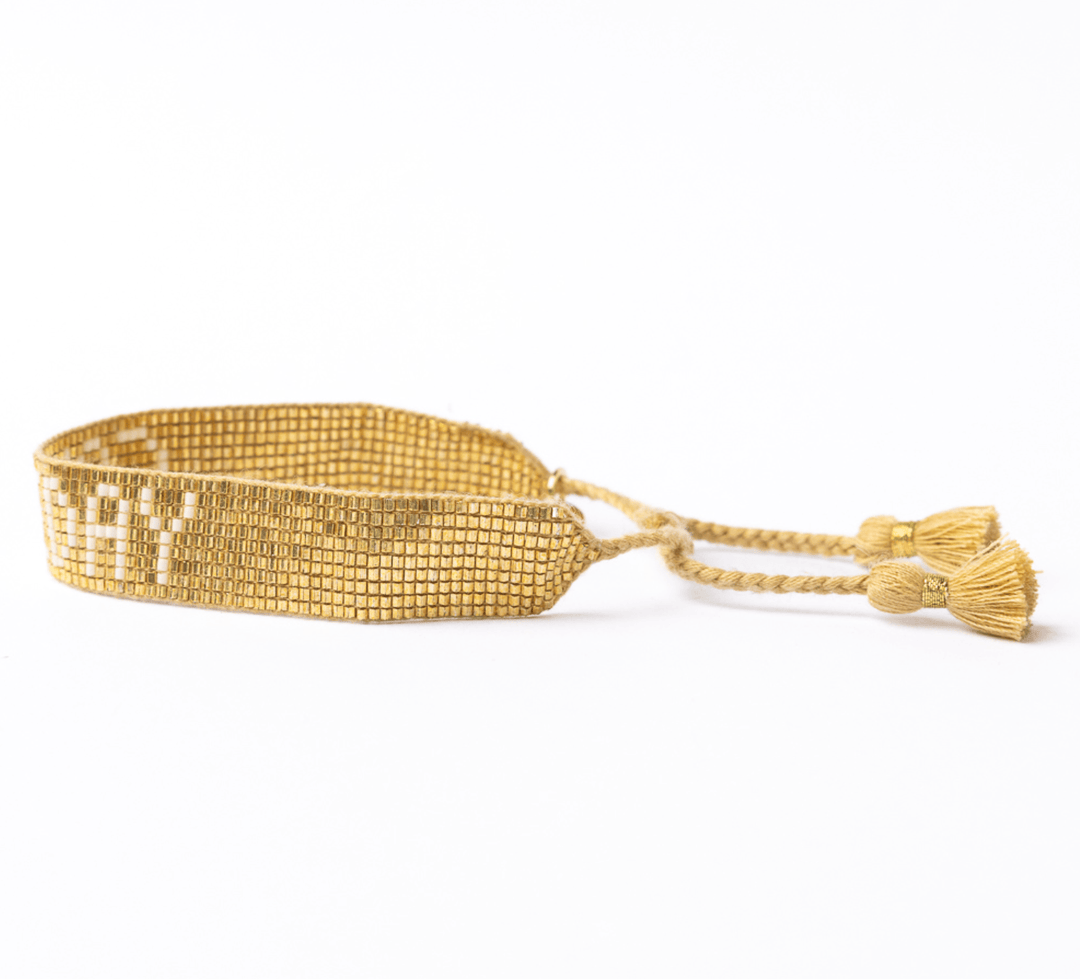 Gold bracelet with tassels on a white background