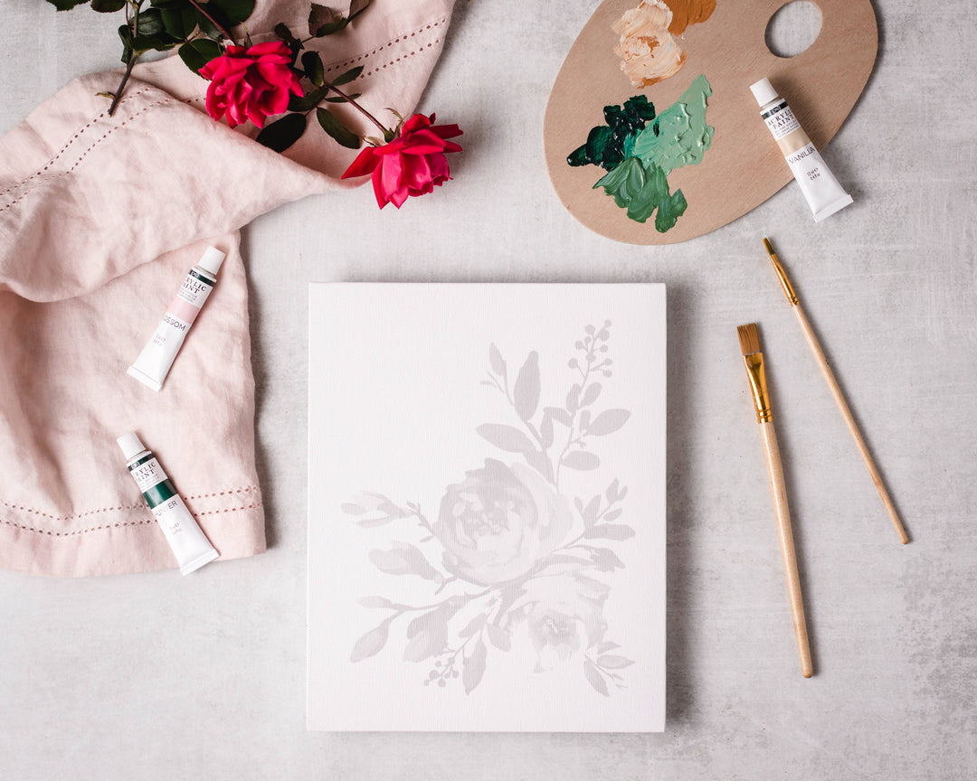 Floral design on paper with art supplies including paint, brushes, and flowers.
