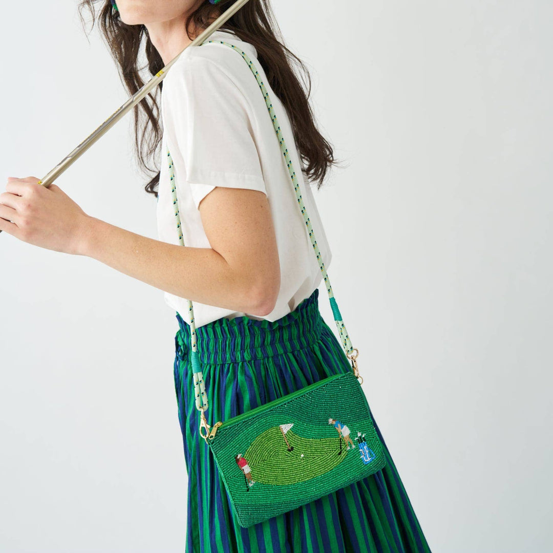 Person wearing a green beaded handbag with a white background