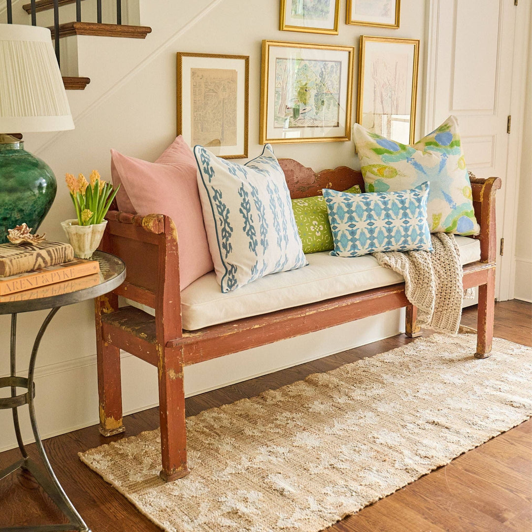 Natural fiber rug under wooden bench with colorful pillows in a living room setting