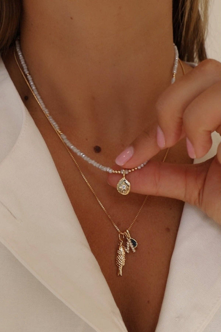 Close-up of a person wearing multiple necklaces with pendants.