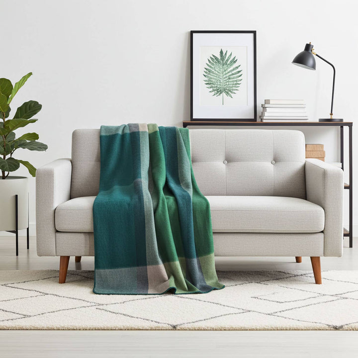 Green plaid blanket draped over a gray sofa in a living room setting.