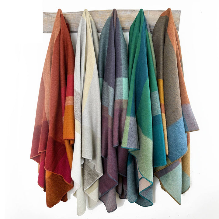 Set of colorful blankets hanging on a wooden rack against a white background