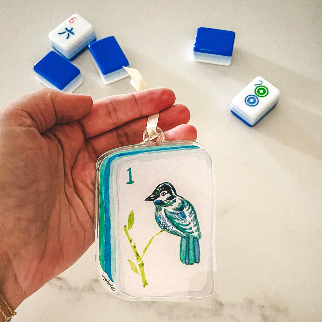 Hand holding an acrylic bam bird mahjong tile ornament.