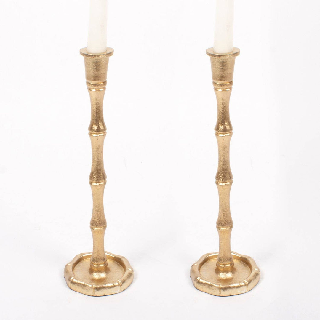 Two gold candle holders with candles on a white background