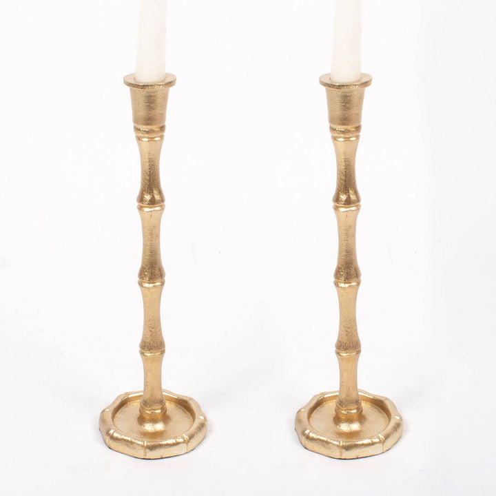 Two gold candle holders with candles on a white background