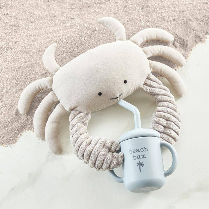 Plush crab toy with a 'beach bum' mug on sand