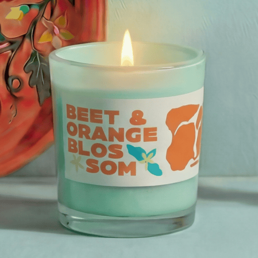 Candle with a label reading 'Beet & Orange Blossom' on a light background