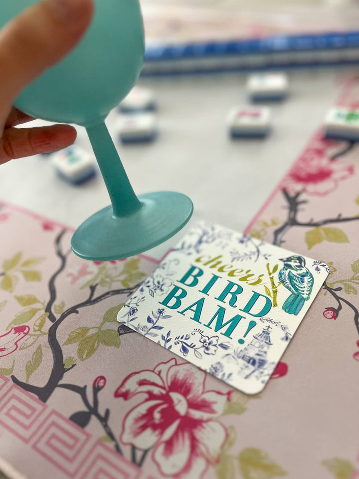 Bird Bam coaster on a table with teal wine glass.