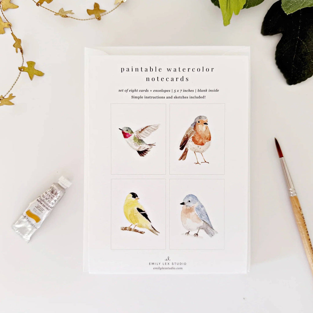 Set of paintable watercolor notecards with bird illustrations on a white surface.