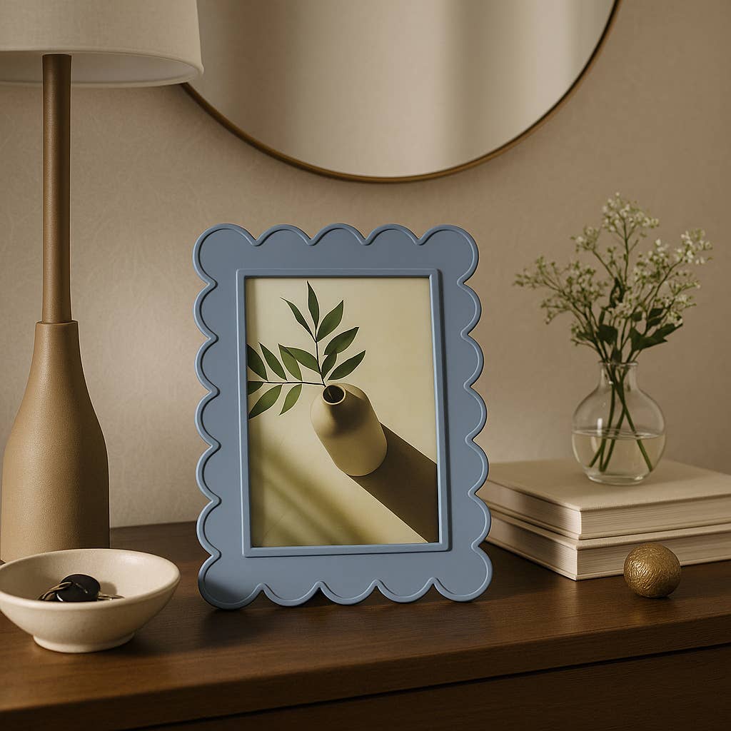 Decorative blue frame with a plant image on a wooden surface with a lamp, vase, and books in the background.
