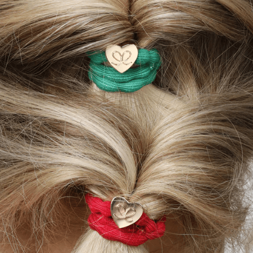 Close-up of a person's hair with green and red hair ties featuring heart designs.