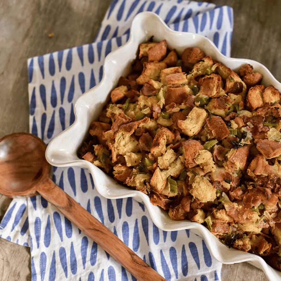 white ruffled casserole dish with breaded casserole and wood spoon