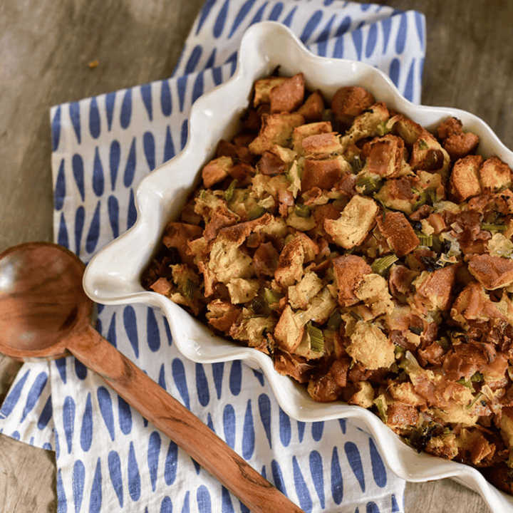 white ruffled casserole dish with breaded casserole and wood spoon
