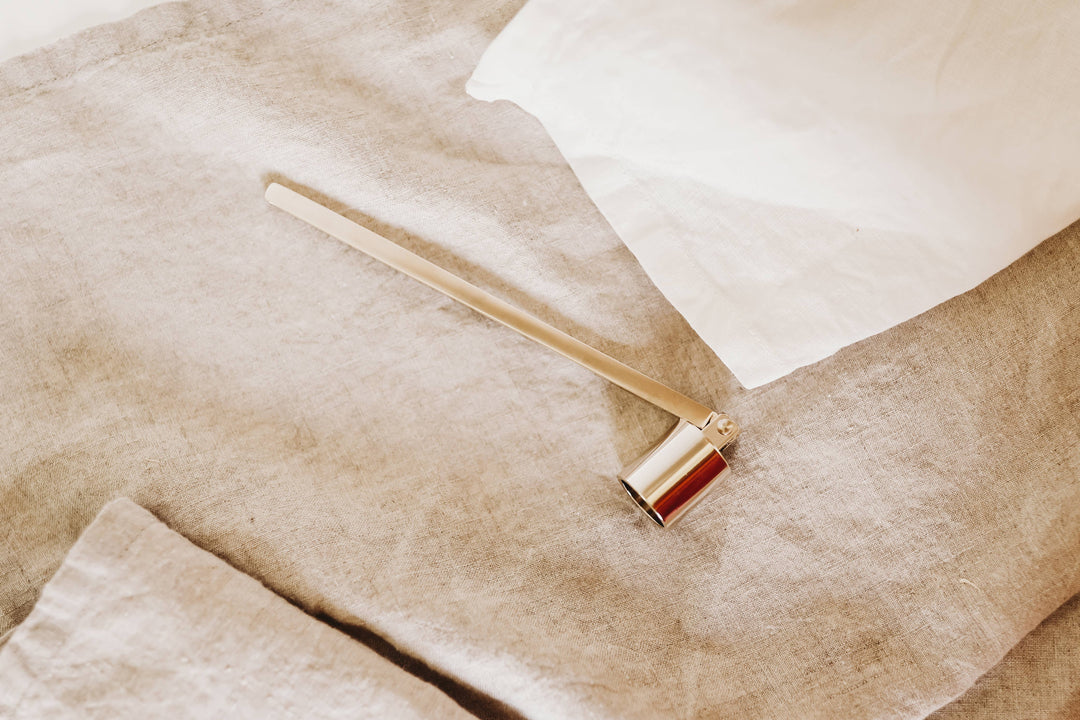 Gold candle snuffer on flax linen fabric.