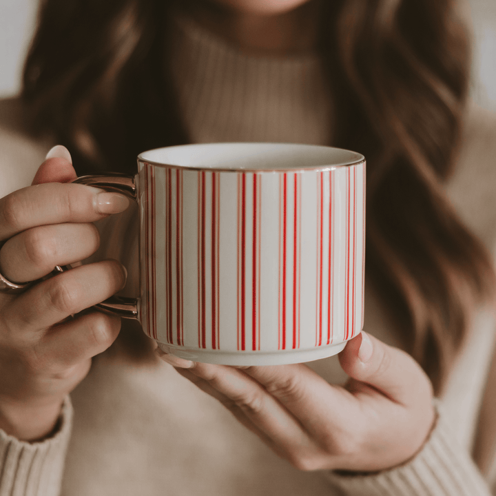 Person holding a mug with red and white striped design