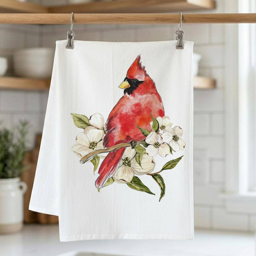 Tea towel with a red cardinal design hanging on a rack in a kitchen.