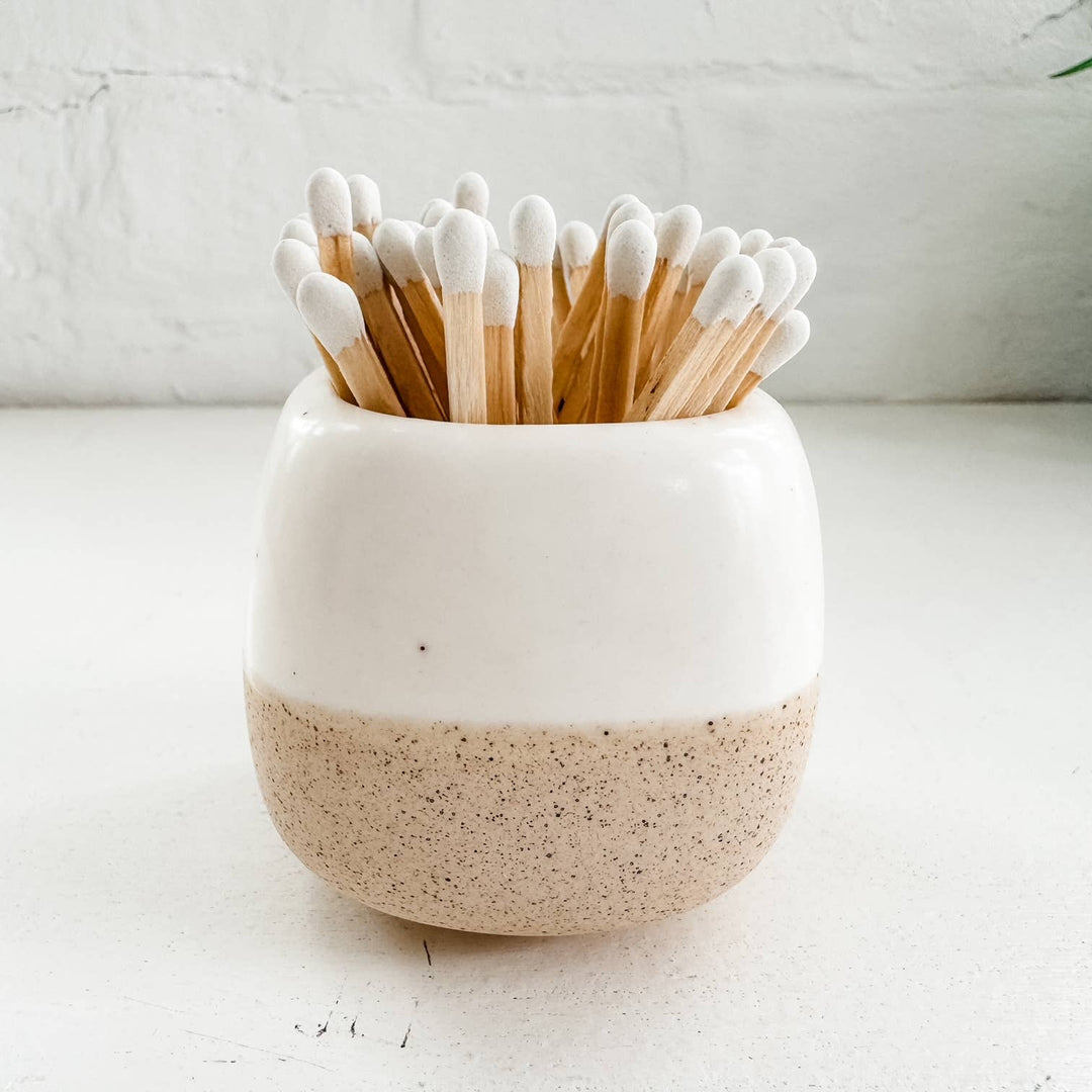 Ceramic match holder with wooden matches on a light background