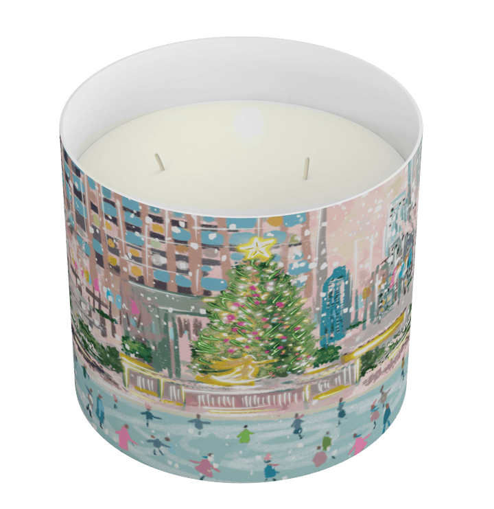 A cylindrical scented candle with a colorful winter city scene printed on the outside, filled with white wax and featuring two wicks, shown on a plain white background.