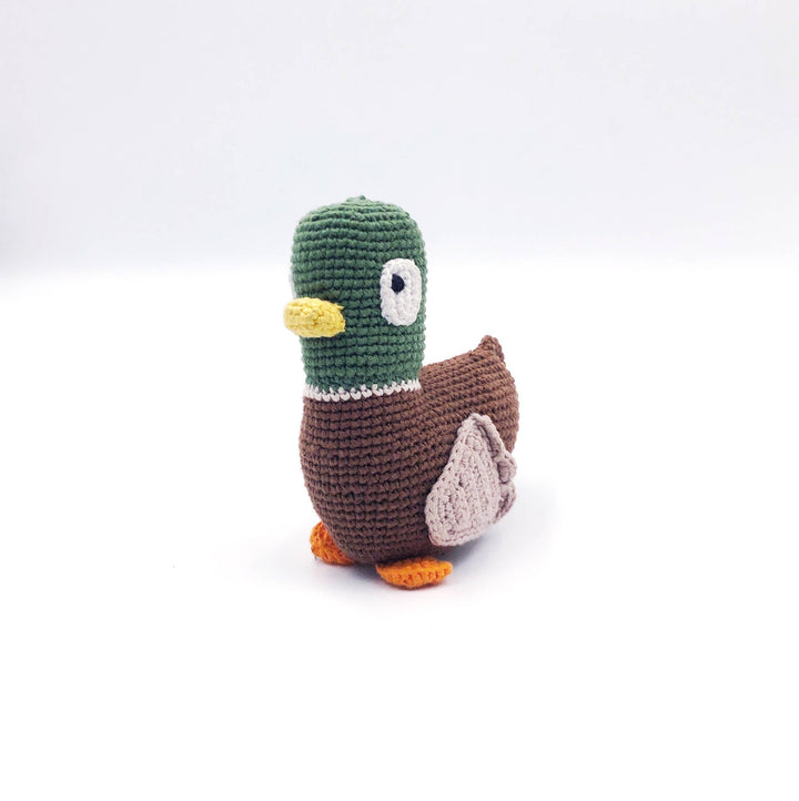 A crocheted toy duck with a green head, brown body, yellow beak, white eye, and orange feet, photographed on a plain white background.